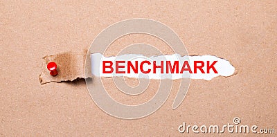 Beneath the torn strip of kraft paper attached with a red button is a white paper labeled BENCHMARK Stock Photo