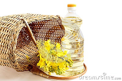 Benefits of rapeseed oil: a bottle of rapeseed oil, a bouquet of flowering branches of rapeseed, a basket of vines on a light Stock Photo