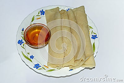 Bengali cuisine - Patishapta Pitha with Jaggery Syrup on a bowl Stock Photo