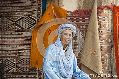 Berber man with turban in front of colorful carpets, Morocco Editorial Stock Photo