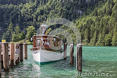 Launch with tourists mooring to wooden pier in lake Konigssee Editorial Stock Photo