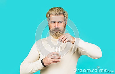 Berded man taking drugs to releave headache. Man taking pill against headache. Male taking a pill with a glass of water Stock Photo