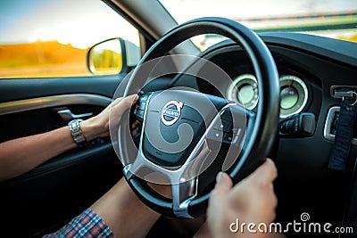 Driver in shorts holds a Volvo steering wheel Editorial Stock Photo