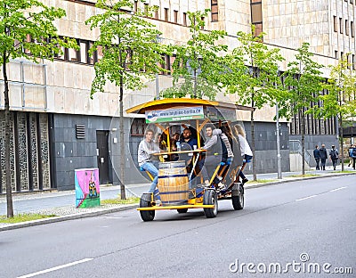 BERLIN, GERMANY. Young people ride a tourist bike car down the street Editorial Stock Photo