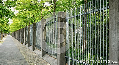 Tree-lined sidewalk with beautifully geometric fence Stock Photo