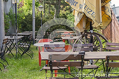 View into a beer garden with various mixed garden furniture and old wooden cart wheels Editorial Stock Photo