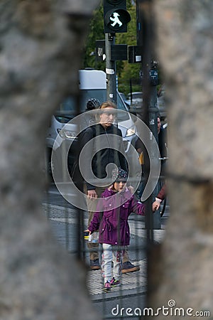 BERLIN, GERMANY - SEPTEMBER 26, 2018: Contrasting and curious perspective through a hole of the Berlin Wall of a child Editorial Stock Photo