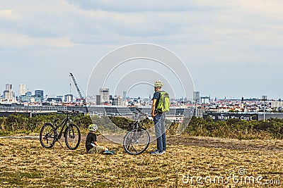 Man and boy resting beside their bicycles on the `Teufelsberg` devil hill, looking at the skyline of Berlin Editorial Stock Photo