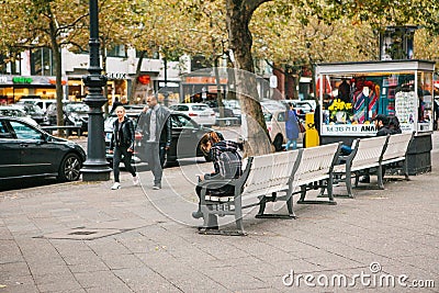 Berlin, October 2, 2017: Young multiethnic couple strolling along Berlin streets next to people sitting on benches Editorial Stock Photo