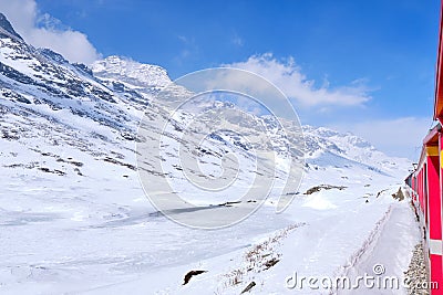 Bernina mountain pass. The famous red train is crossing the white lake. Amazing landscape of the Switzerland land. Famous Editorial Stock Photo