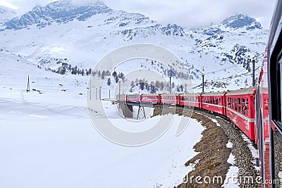 Bernina mountain pass. The famous red train is crossing the white lake. Amazing landscape of the Switzerland land. Famous Editorial Stock Photo