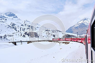 Bernina mountain pass. The famous red train is crossing the white lake. Amazing landscape of the Switzerland land. Famous Editorial Stock Photo