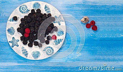 Berries, raspberries, blackberry, blueberries, bramble, dewberry, plate, blue background, small fruity, grain, seed, kernel, granu Stock Photo