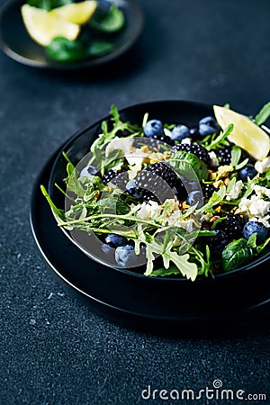 Berry (blackberry, blueberry) and arugula salad with feta, pistachios and basil Stock Photo