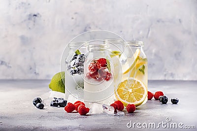 Berry and citrus soft drinks and cocktails in glass bottles on gray stone table background, copy space Stock Photo