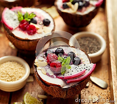 Berry smoothie in a coconut bowl with fresh Pitaya fruit Dragon fruit, blueberries and raspberries, mint, almond flakes, chia se Stock Photo