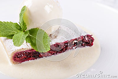 Berry strudel cake served with ice cream, mint leaf and vanilla sauce. Classical austrian dessert on white plate. Sweet Stock Photo