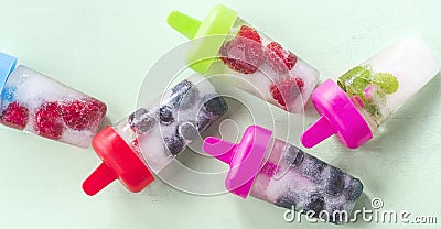 Berry summer ice lolly with raspberries, blueberries, mint leaves on a green mint background, wide composition Stock Photo