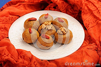 Besan laddu, handmade vegan sweets with wallnuts and goji berries on orange ethnic cloth Stock Photo