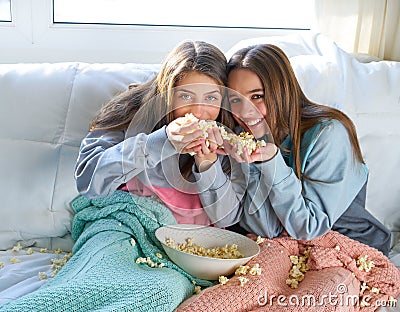 Best friend girls at sofa having fun with popcorn Stock Photo
