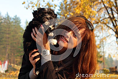 Young women smiling while holding her cuddly puppy in arms Stock Photo