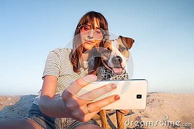 Best friends concept: human taking a selfie with dog. Young female makes self portrait with her puppy outdoors on a beach Stock Photo