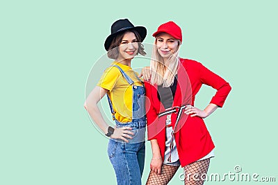 Best friends spending great time together. Portrait of two beautiful happy fashionable hipster girls standing and posing, looking Stock Photo