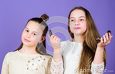 The best make up and beauty products. Make up artists holding lipstick and compact powder. Cute small girls wearing face Stock Photo