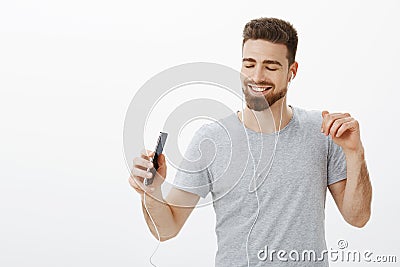 Best music app ever. Joyful charismatic carefree handsome man with beard and sick eyebrows closing eyes from delight and Stock Photo