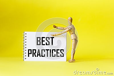 Best practices, the text is written on a notebook, next to a wooden doll on a yellow background. Stock Photo