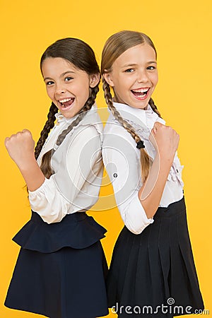 Best pupils award. Excellent pupils. Girls perfect uniform outfit on yellow background. Making everything right Stock Photo
