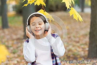Best song about fall. Cute small child enjoy song playing in headphones. Adorable little girl sing along to song. Autumn Stock Photo