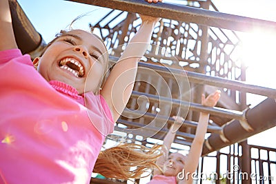 The best things in life arent things. two little girls hanging on the monkey bars at the playground. Stock Photo