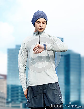 Best time ever. a young jogger checking the time while out for a run in the city. Stock Photo