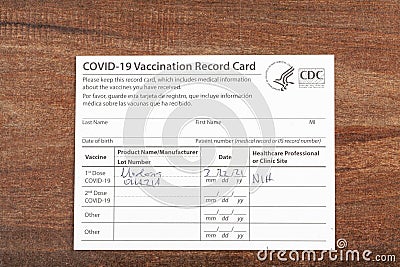 Close up isolated image of a COVID 19 vaccination record card on a wooden desk Editorial Stock Photo