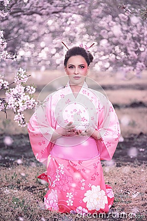 Beuatiful girl in japanese traditional kimono in peach orchard during spring Stock Photo