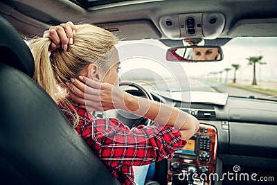 Beutiful blond girl comb her hair with a rearview mirror in car Stock Photo