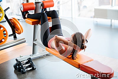 Beutiful woman athlete doing abdominal crunches on bench in gym Stock Photo