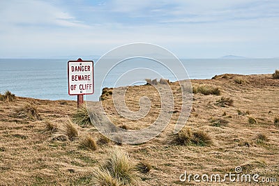 Beware of cliff warning sign, coastal landscape Stock Photo