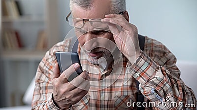 Bewildered old man looking at cellphone, new technology complicated for elderly Stock Photo