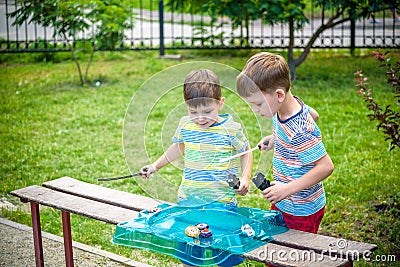 Two boys playing with a Beyblade, spinning top kid toy. Popular Stock Photo