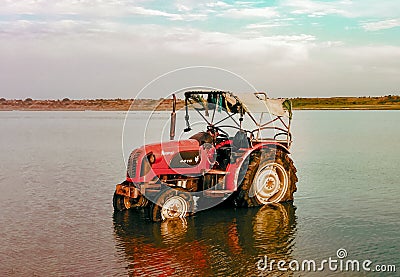 Cleaned Tractor standing in Water, Reflection seen in river water Editorial Stock Photo