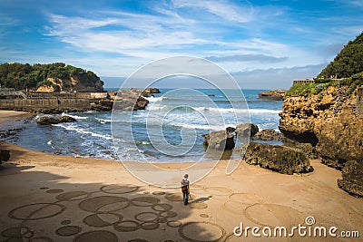 Biarritz, France - October 4, 2017: upper view on man artist creating sand drawing with wooden stick Editorial Stock Photo