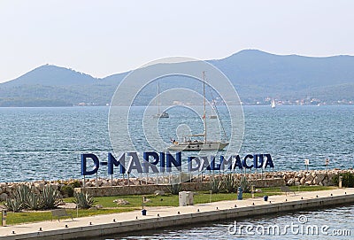 Bibinie, D-Marina, Croatia - sept 9 2018: Logo at the etnrance in mediterranean marina near Sukosan town. The sailing boat floatin Editorial Stock Photo