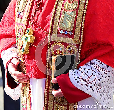bible with in the hands of the bishop during the religious rite with red clerical dress Stock Photo