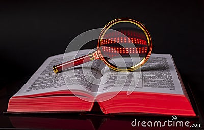 Bible or law code book with magnifying glass for analysis over black background Stock Photo