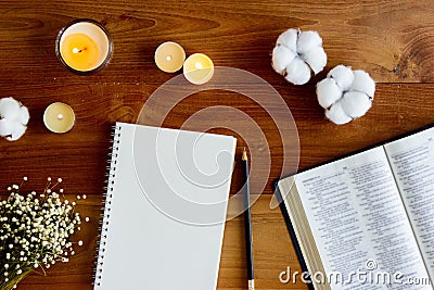 Bible with notebook, candlelight and flower over the wooden background. Stock Photo