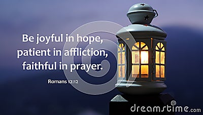 Bible verse quote - Be joyful in hope, patient in affliction, faithful in prayer. Romans 12:12. With lantern light at night. Stock Photo