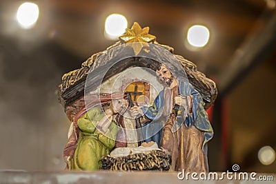 Biblical Mary and Joseph look down on Baby Jesus in the manger in a Christmas nativity scene against bokeh background Stock Photo