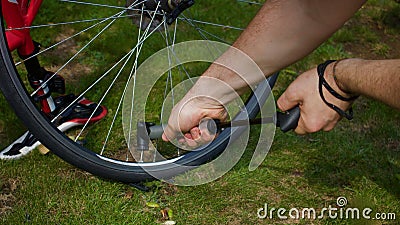 Young man`s hands pumping air into bicycle tyre using hand pump - image Stock Photo